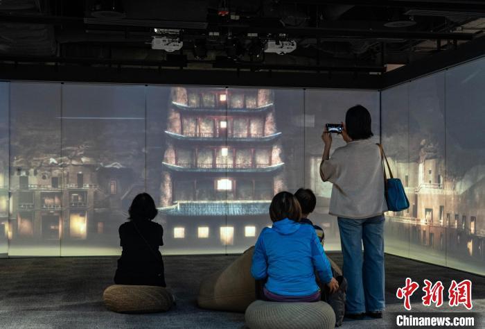 图为观众在展区内欣赏讲述敦煌故事的视频　中新网记者　侯宇　摄