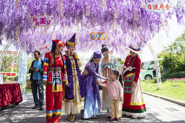 在青海西宁大通县边麻沟花海景区,工作人员与一名同家人来游玩的小朋友互动(2025年7月22日摄)。新华社记者 孙瑞博 摄