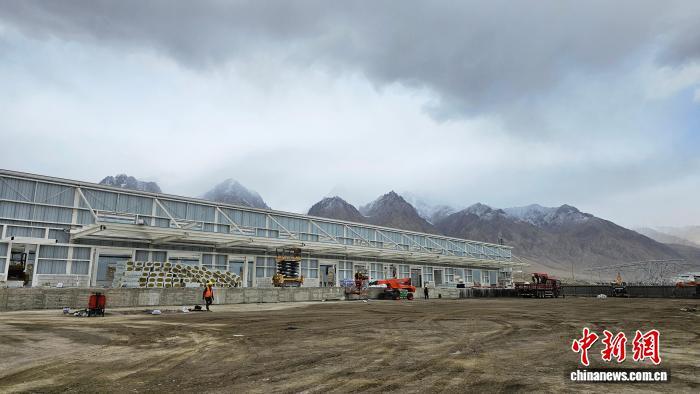 图为雪山下的喀什地区2024年红其拉甫口岸查验基础设施建设项目,工人正在紧张施工。耿金睿 摄