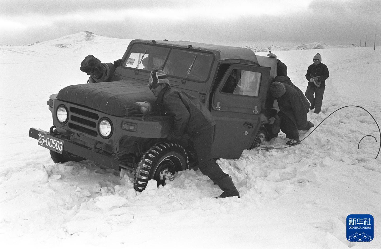 1989年,青藏公路沿线,一辆汽车陷入积雪。这是道班工人协力抬车脱困。(1989年4月29日发)