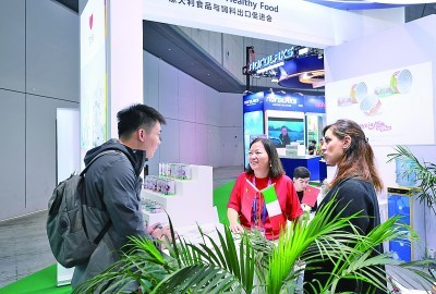 在第八届进博会农食产品展区,参观者(左)在意大利食品与饲料出口促进会展台咨询。新华社发