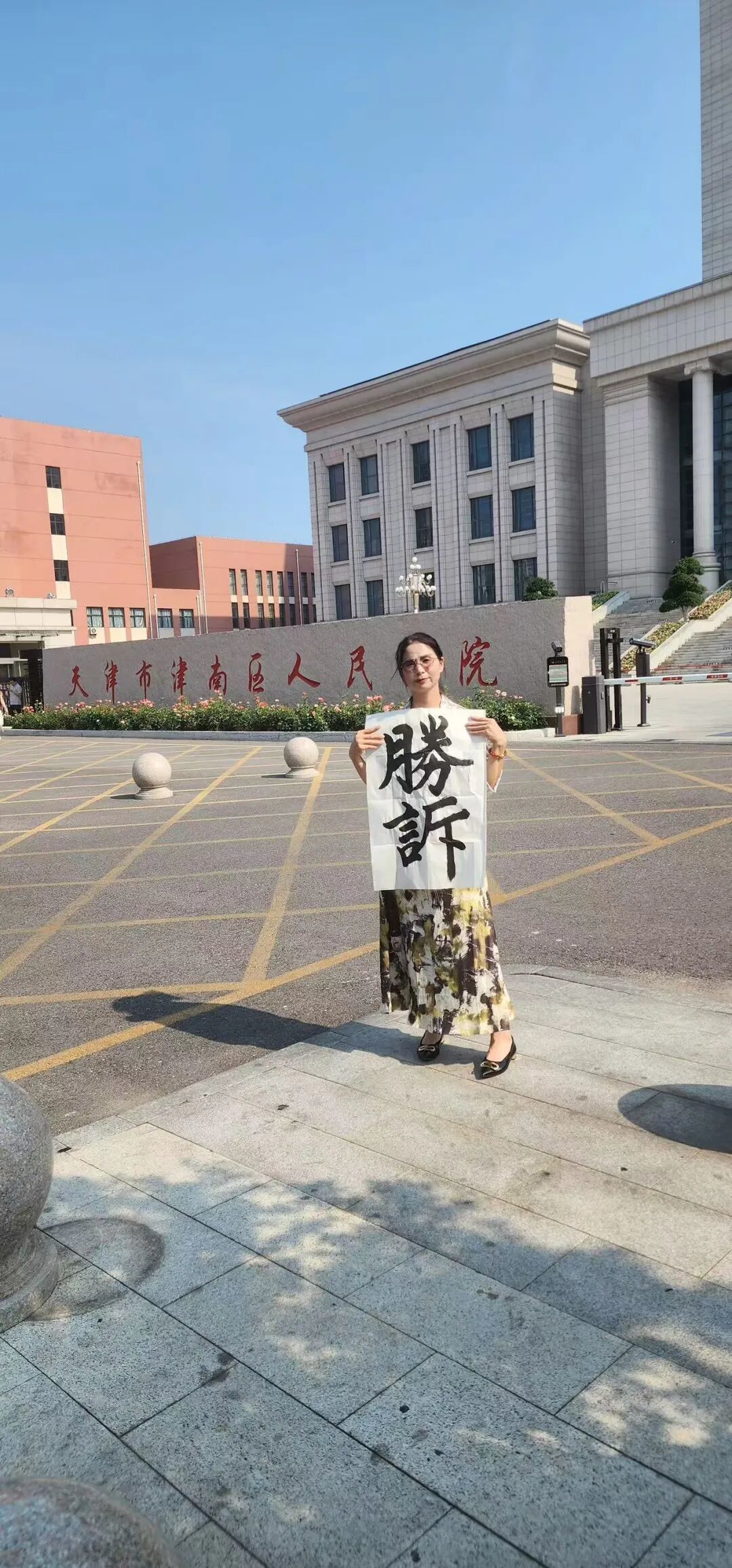 2025 年 7 月18 日,工伤行政诉 讼案胜诉后,崔丽 丽在天津市津南区人民法院前拍照留念。(图/受访者供图)