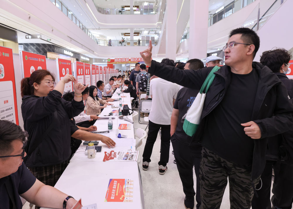 5月17日，在招聘会现场，一名应聘者（前右）用手语与招聘人员交流。新华社记者 殷刚 摄