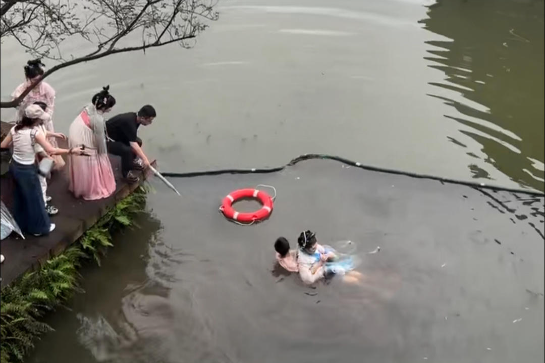 ▲女游客落水,众人施救 视频截图
