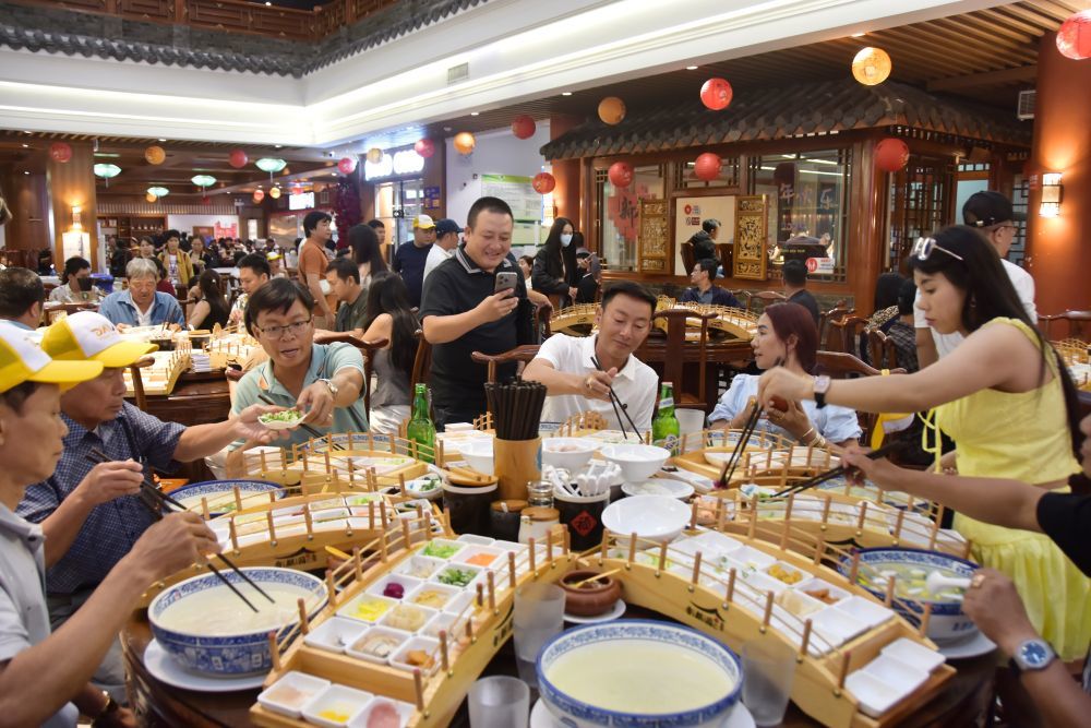 7月12日，来自越南的游客在云南省蒙自市一过桥米线店享用过桥米线。新华社发（薛莹莹 摄）