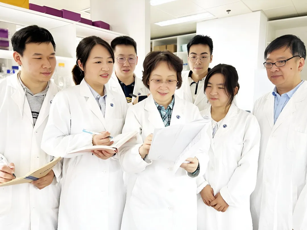 雷群英教授(前排居中)与团队在实验室讨论。复旦大学 供图