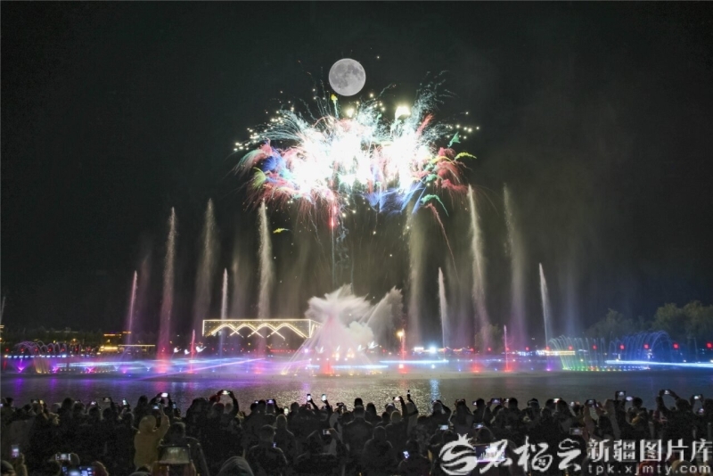 10月6日晚,新源县天鹅湖景区、大型激光水舞烟花秀与圆月同框。张文庭 摄