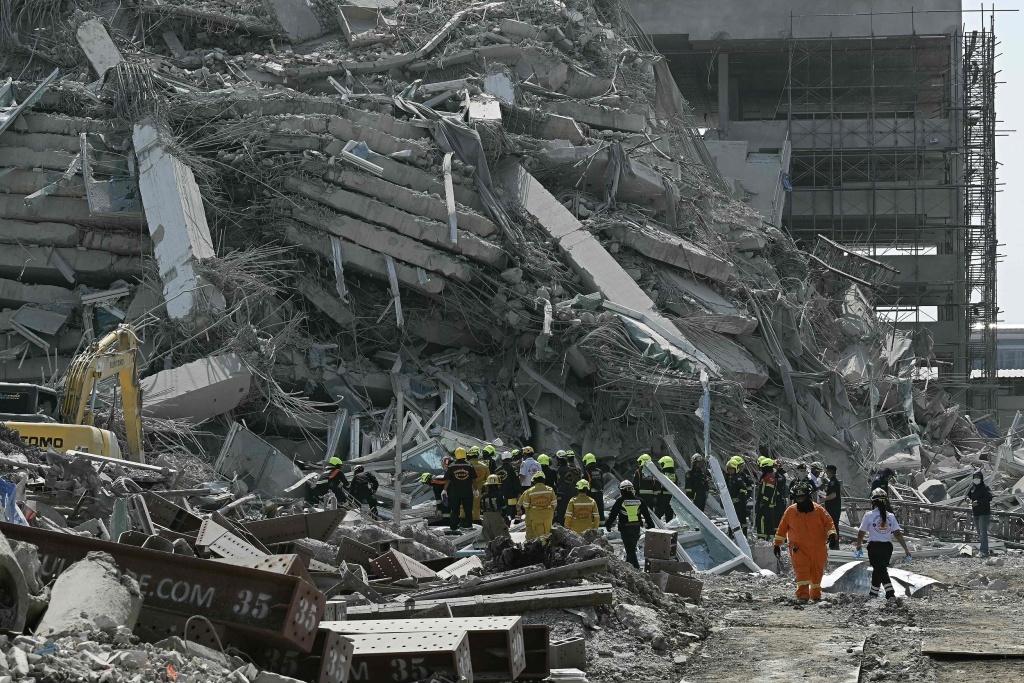 当地时间3月28日,泰国曼谷,一座建筑物在地震后倒塌,救援队正在施工现场进行救援。