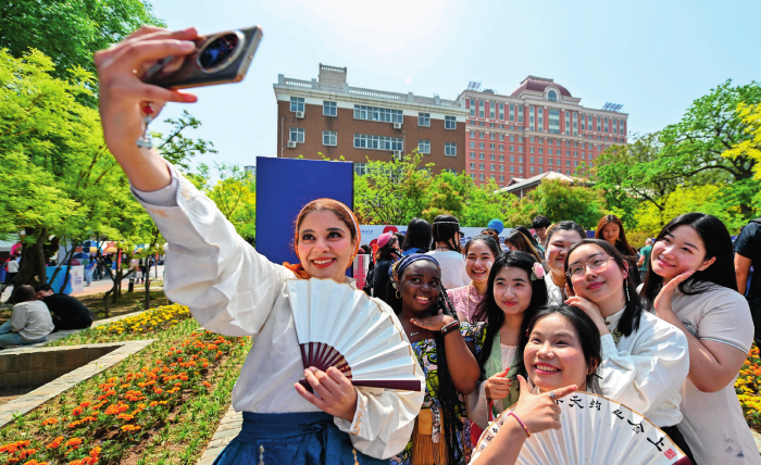 中外青年在以“上合之约天外同彩”为主题的天津外国语大学第八届国际文化节上合影留念（2025 年 4 月 20 日摄）孙凡越摄 / 本刊