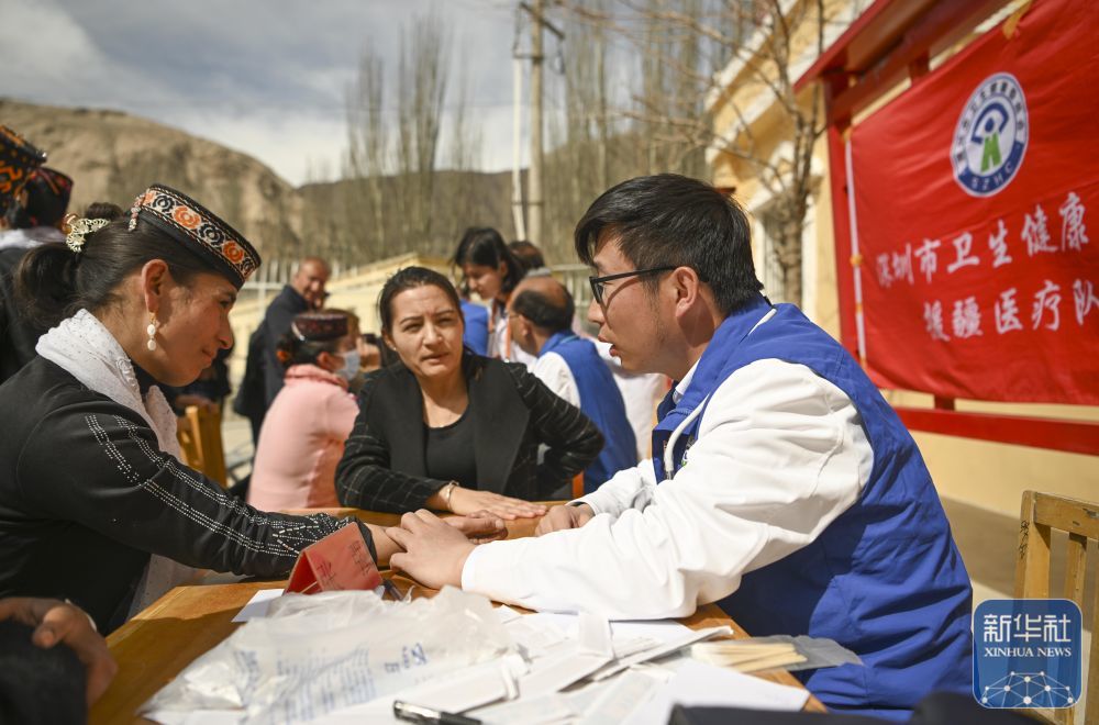 ↑ 在新疆塔什库尔干塔吉克自治县库科西鲁格乡卫生院，深圳援疆医生张强（右一）为村民把脉（2025年3月24日摄）。新华社记者 胡虎虎 摄