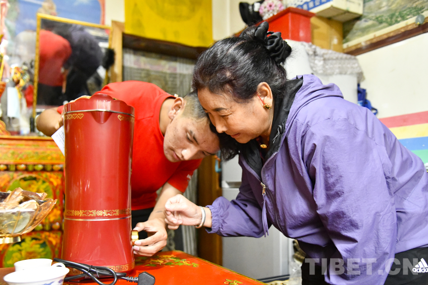 图为卓嘎与儿子罗布次仁一起仔细研究这一台全自动酥油茶壶的使用 摄影:赵振宇