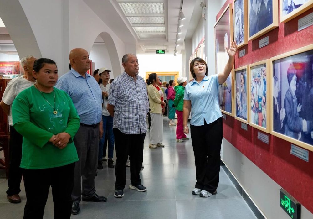 在新疆和田地区于田县库尔班&middot;吐鲁木纪念馆，如克亚木（右一）向参观者介绍展出的照片（2025年9月14日摄）。新华社记者丁磊摄