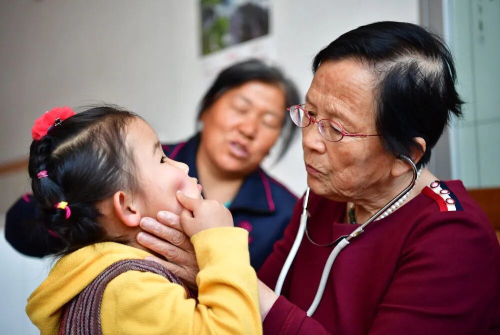 2018年4月29日,路生梅(右一)在家中给一名小朋友看病。新华社记者 邵瑞 摄