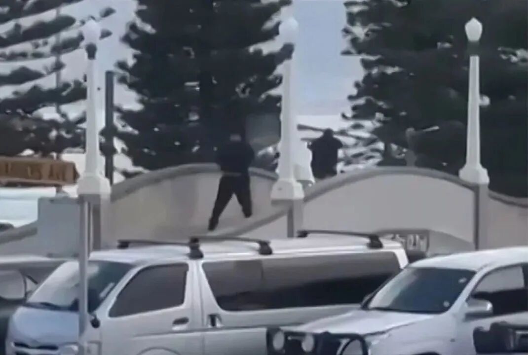 This screen grab made from UGC handout video footage courtesy of Timothy Brant-Coles shows two gunmen dressed in black firing multiple shots on a bridge at Bondi Beach in Sydney on December 14, 2025.