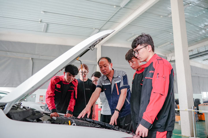 2025年6月27日，在新疆和田技师学院，北京援疆教师李宝（右三）和当地教师一同指导学生维修汽车。新华社记者 徐宏岩 摄