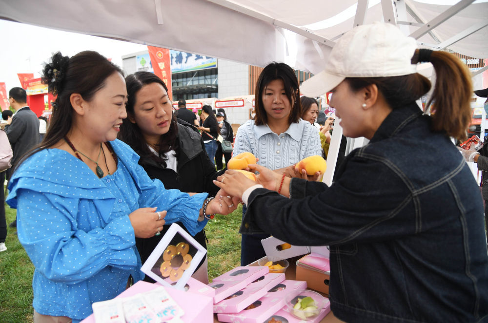 9月19日,北京市平谷区举办2025年中国农民丰收节暨第36届北京农民艺术节“乡村大舞台”平谷区专场展演。工作人员(右一)在活动现场向市民介绍农产品。新华社记者 任超 摄