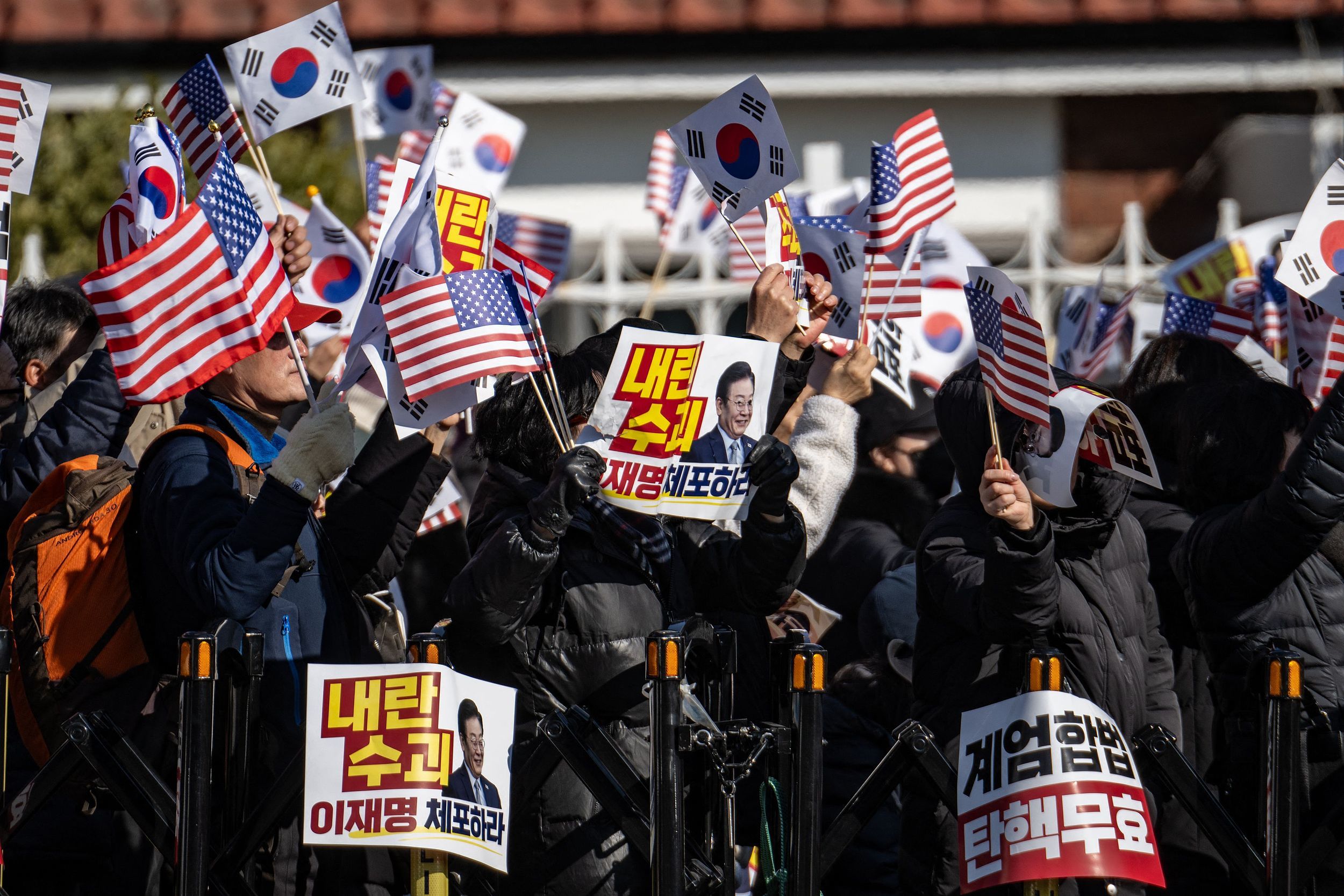 当地时间2025年1月2日，韩国首尔，总统府附近，民众挥舞着美国和韩国国旗，支持被弹劾的韩国总统尹锡悦。视觉中国 图
