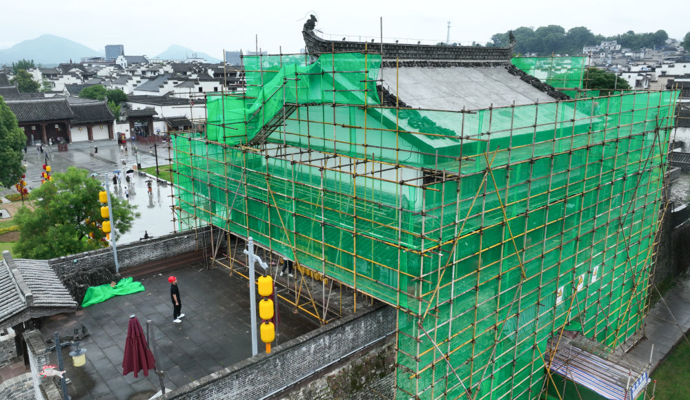 6月19日,周虎(左下)在歙县徽州古城南谯楼保养维护工程现场查看。