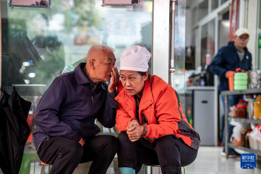 在昆明市幸福家园小区爱心食堂,王兰兰与一名老人交谈(5月28日摄)。