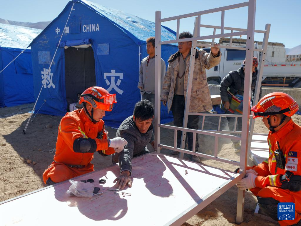 1月8日，在日喀则市定日县措果乡雪珠村安置点，林芝市森林消防支队米林中队的救援人员帮助受灾群众安装领取到的床。新华社记者 沈伯韩 摄