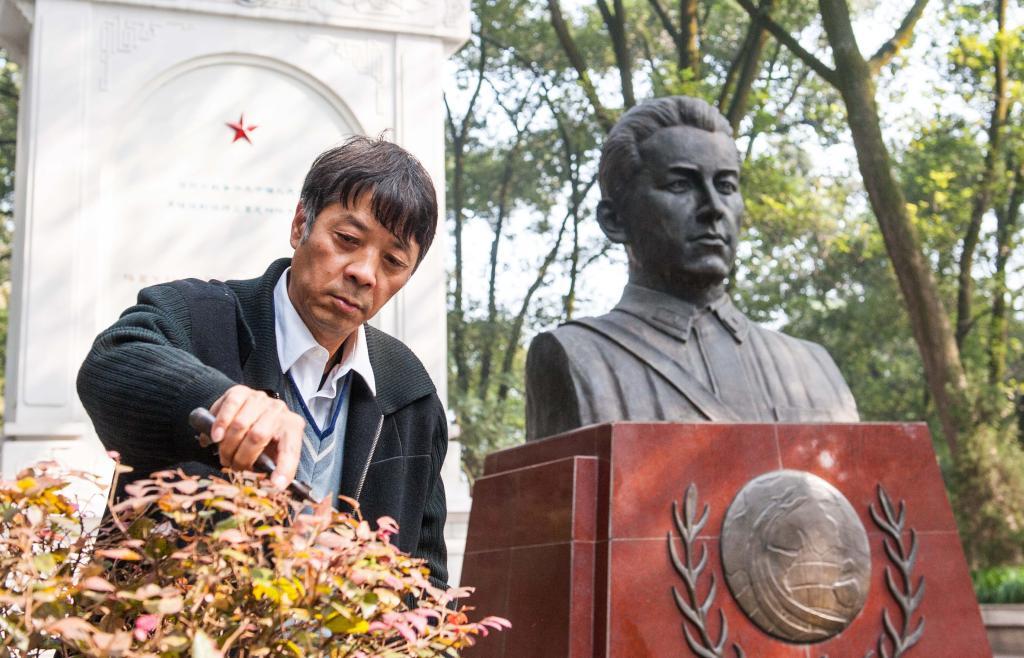 2014年11月19日，守陵人魏映祥在库里申科烈士陵园内库里申科烈士雕像前修剪陵园内的苗木。新华社记者 刘潺 摄