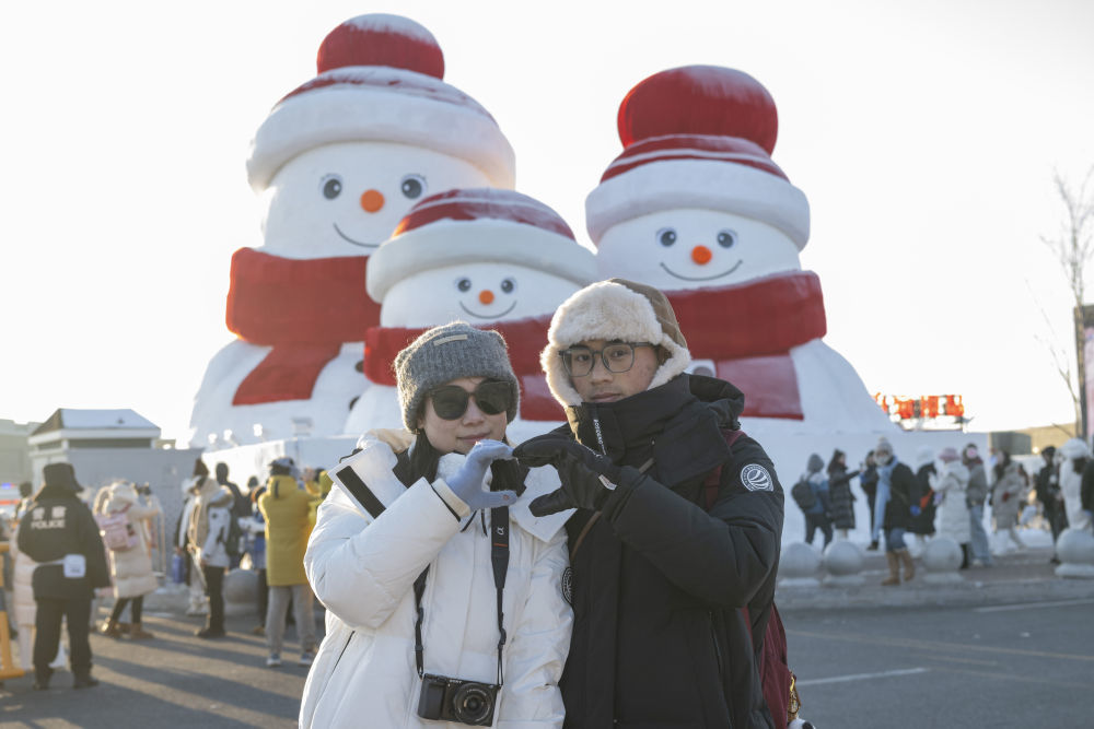 ↑1月3日，在哈尔滨冰雪大世界，游客在“雪人一家三口”附近拍照。新华社记者 谢剑飞 摄