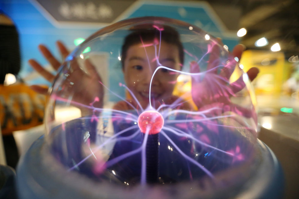 10月3日,小朋友在江苏扬州科技馆体验“辉光球”。新华社发(孟德龙摄)