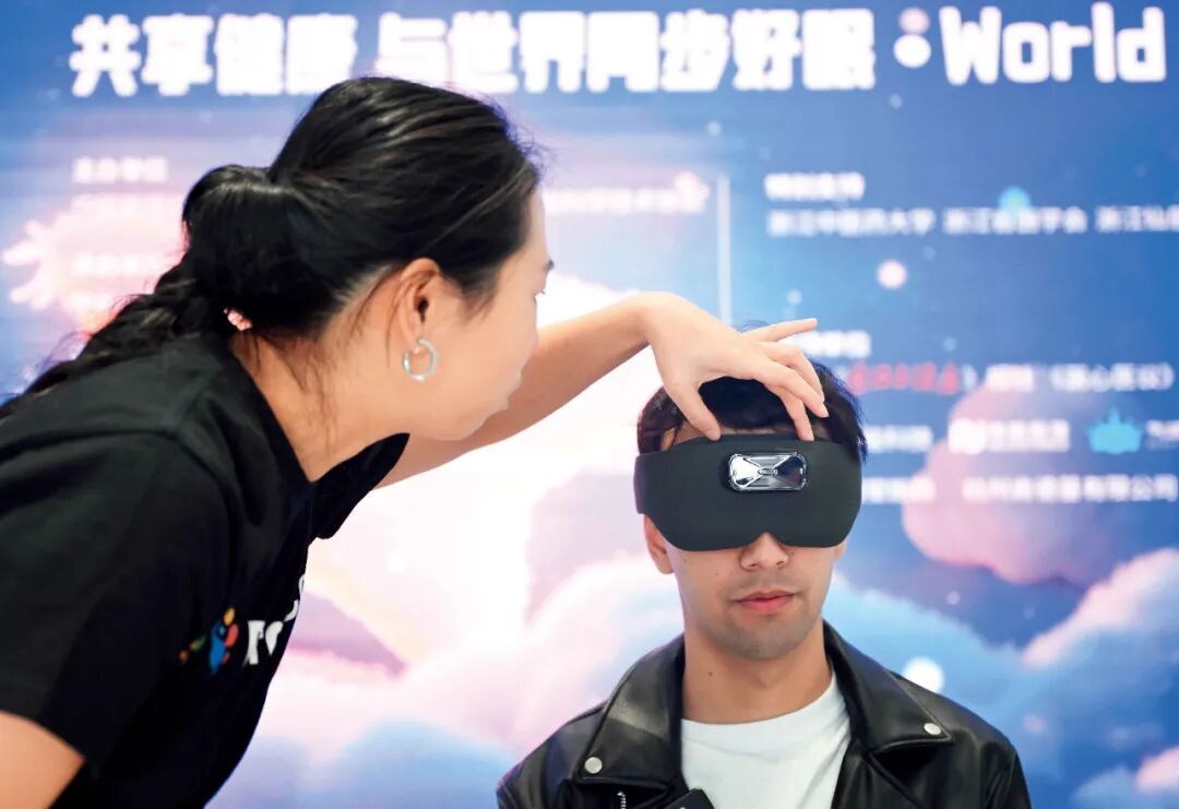 2025年3月21日,在浙江杭州的世界睡眠日“每天早睡一小时”公益活动期间,参与者体验安睡仪。该仪器在采集脑电波后,通过人工智能算法判断神经状态,进而以声光电干预来帮助睡眠。图/中新