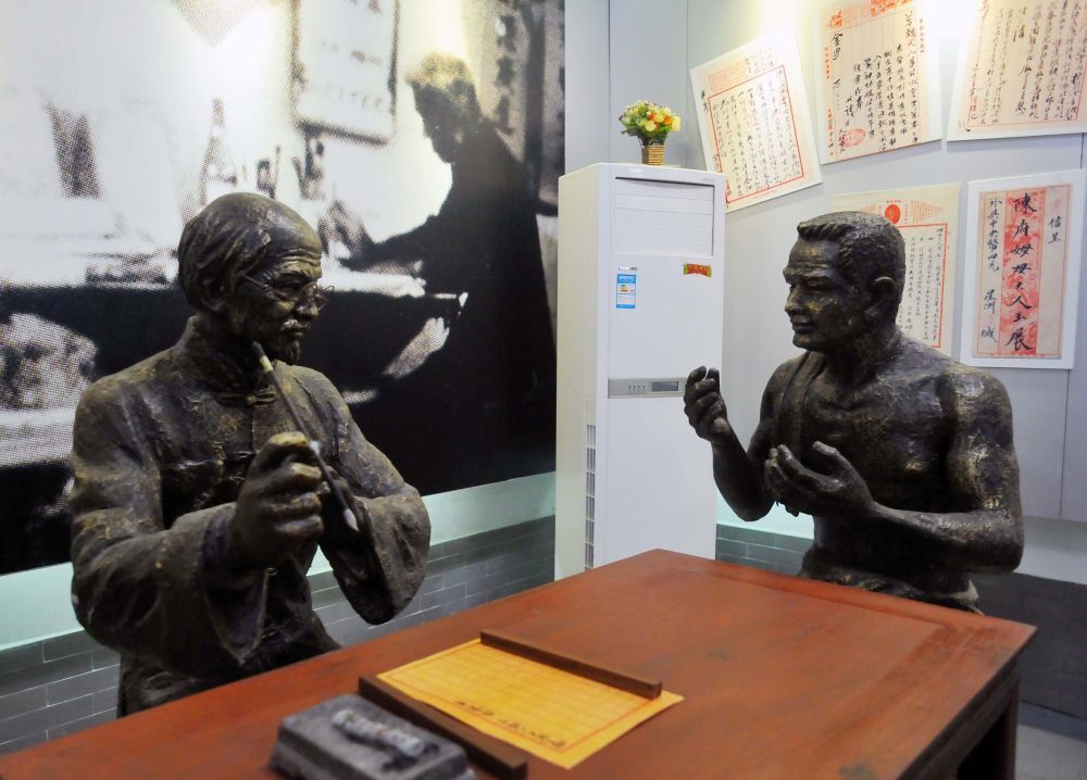 这是汕头侨批文物馆内的一处雕像，展示了一位华侨请知书识字的老先生代为撰写侨批的场景。