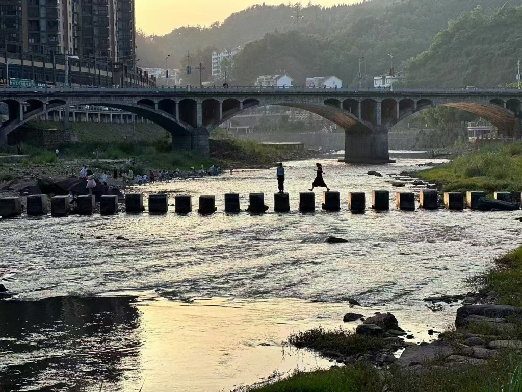 空间所在湖南某学校门口的河流和石桥,志愿者和同学们在桥上行走(曹笛 供图)