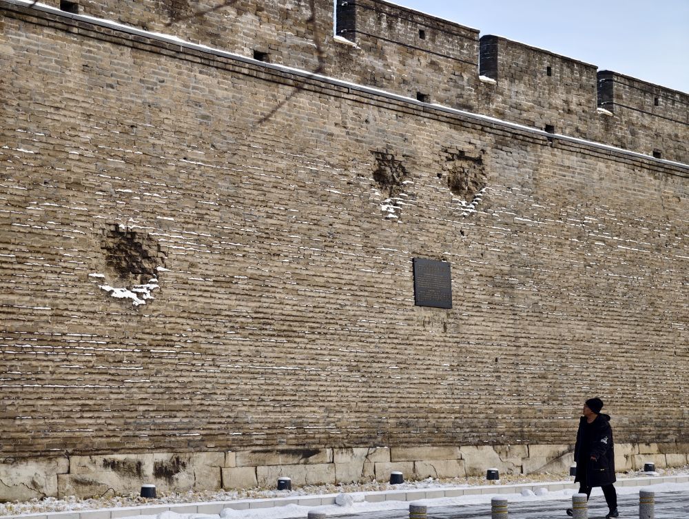 图为游客走过布满弹坑的宛平城墙。新华社发