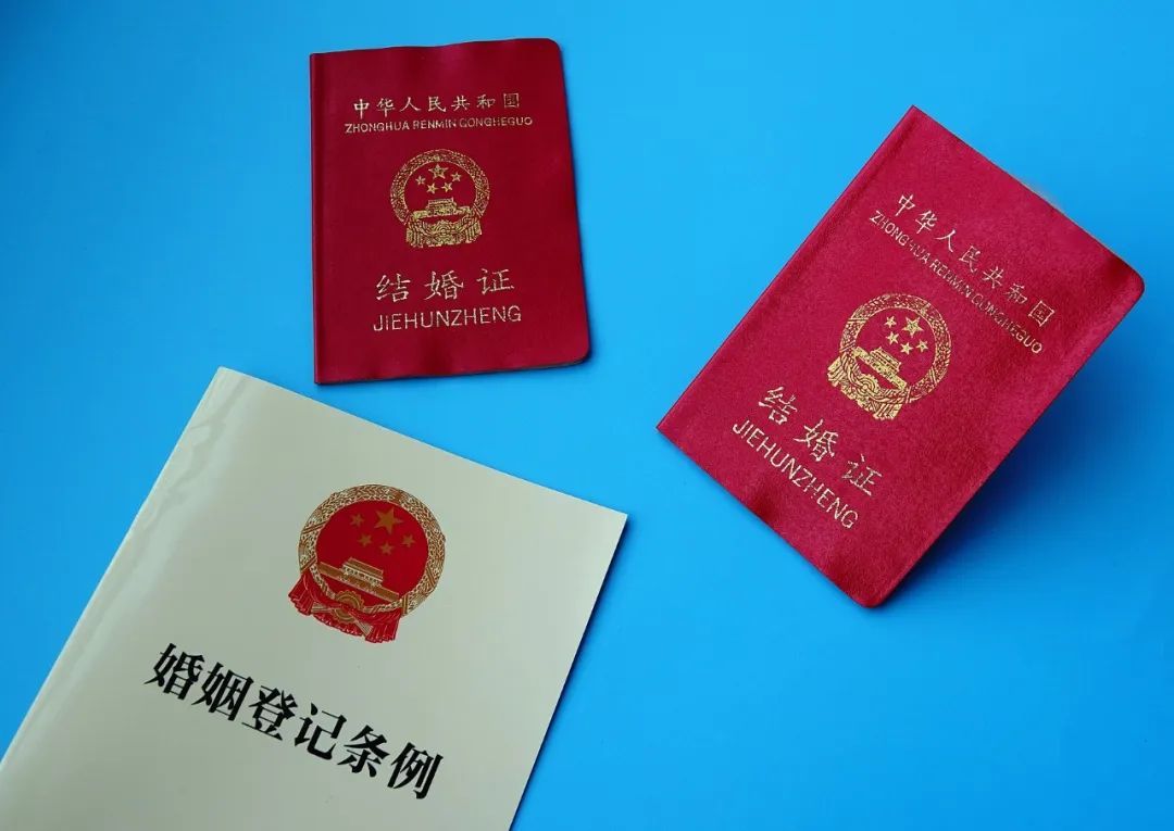 2025年4月21日，湖北宜昌，市民展示新修订的《婚姻登记条例》及结婚证。（图/视觉中国）