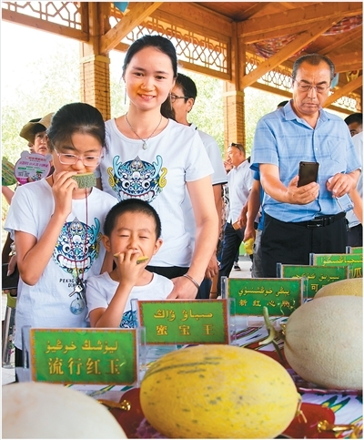 游客在哈密瓜节上品尝哈密瓜。