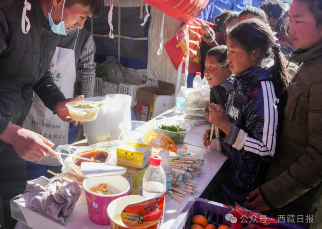 △1月8日，在日喀则市定日县长所乡森嘎村的临时安置点，当地群众马仁（左一）为受灾小朋友免费供应面食