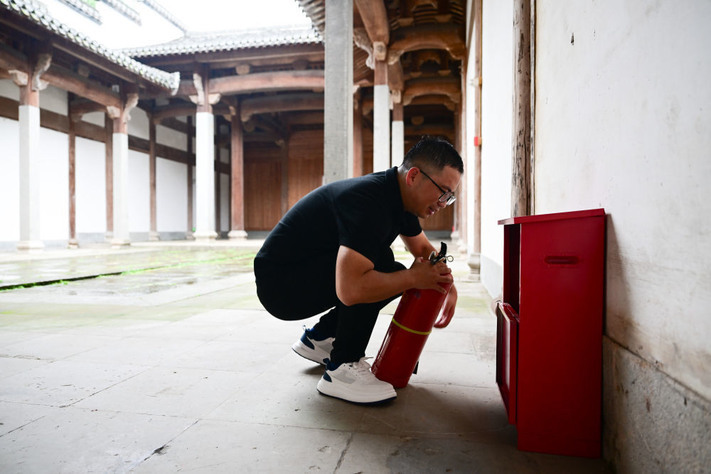 6月19日,周虎在歙县一个祠堂内检查灭火器。