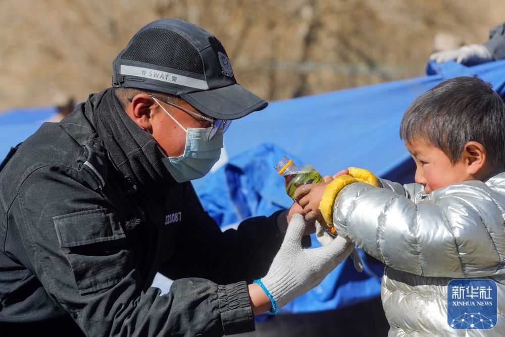 1月10日，在定日县长所乡古荣村，一名警察为孩子拧开饮料瓶盖后，孩子将饮料递给他喝。新华社记者 沈伯韩 摄