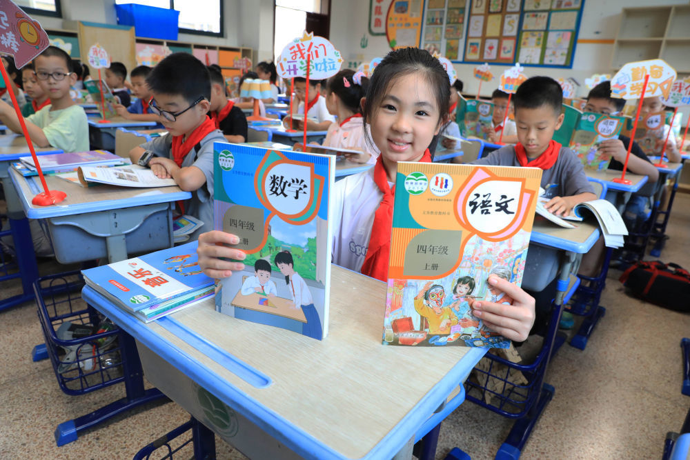 8月30日,在浙江省舟山市南海实验学校惠民桥小学校区,一名四年级的学生展示刚领到的新课本。新华社发(陈永建摄)