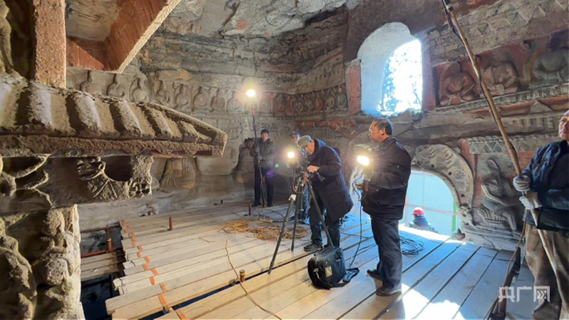 文保人员在洞窟里对造像进行拍摄存档(央广网记者 张晋鹏 摄)