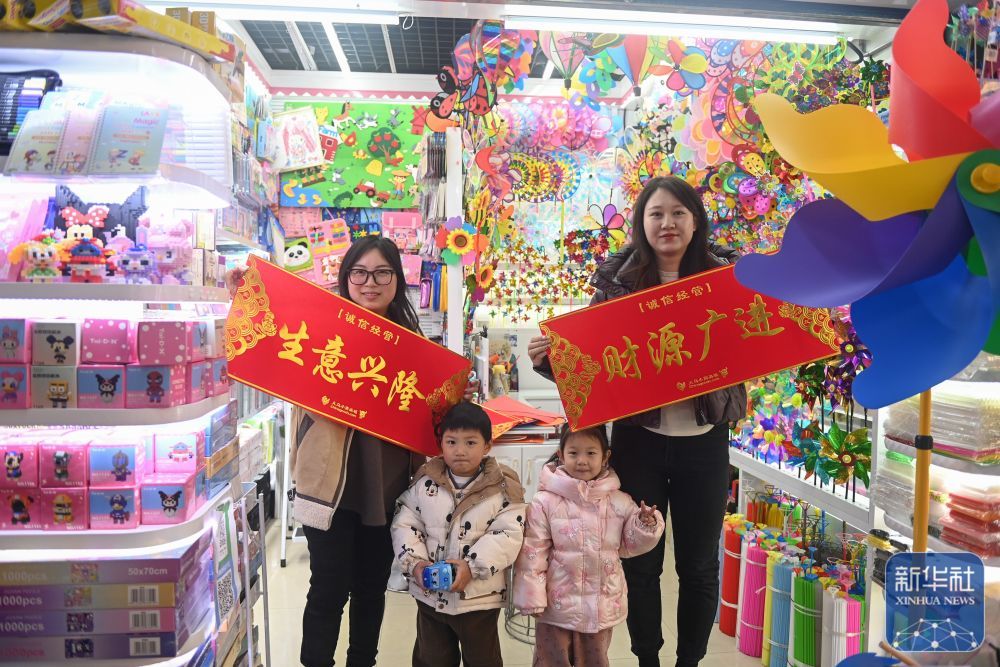↑2月9日,义乌国际商贸城的商户在店铺门口展示领取的新春横幅。