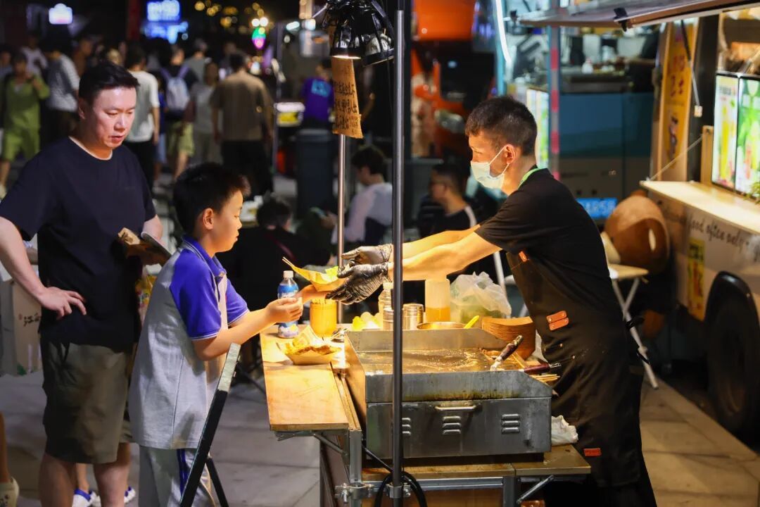 地攤市集上購買小吃的消費者 / 新華社記者王翔 攝