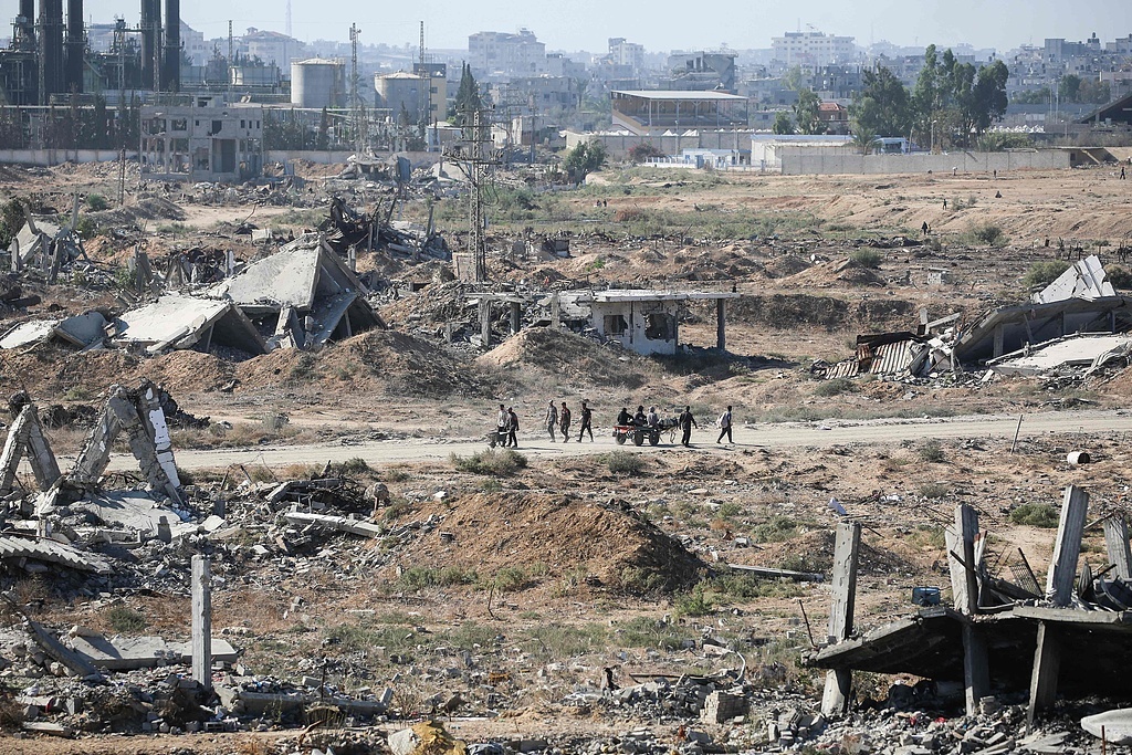 10月14日,加沙地带中部,流离失所的居民返回家园,巴勒斯坦人走过被毁的建筑物。(视觉中国)
