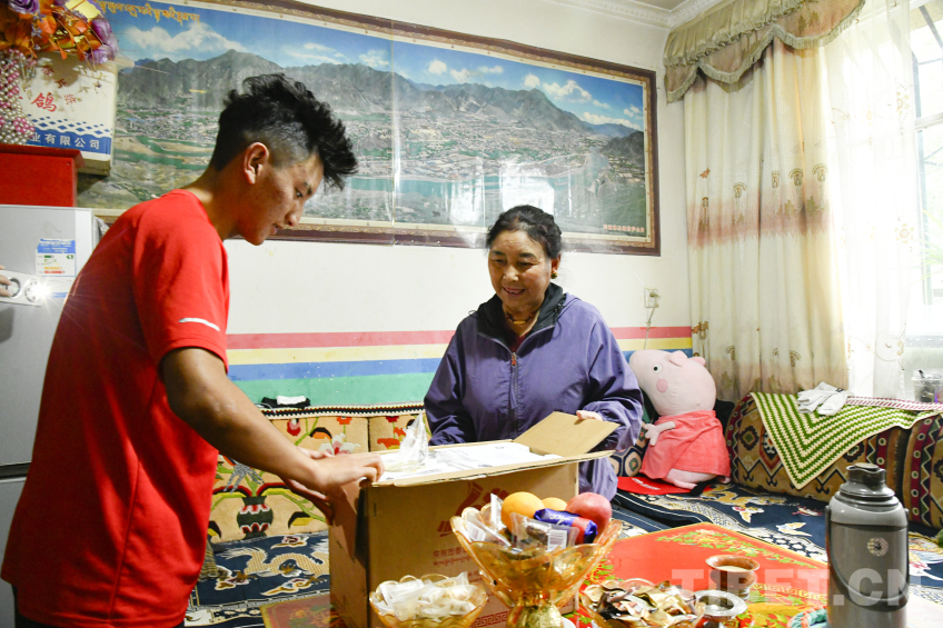 图为卓嘎与儿子罗布次仁一起郑重打开中央代表团赠送的全自动酥油茶壶包装 摄影:赵振宇