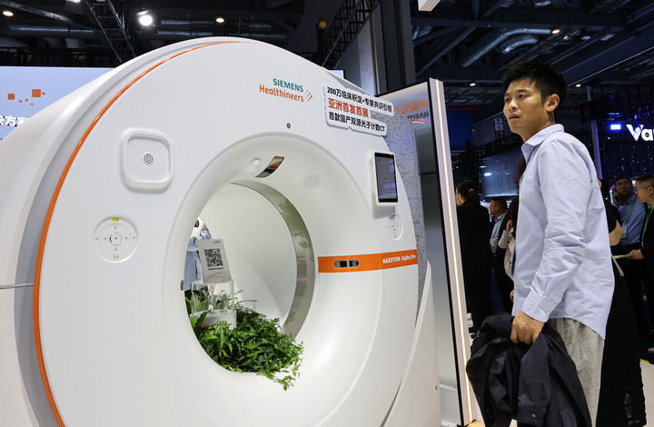 2025年11月6日,参观者在进博会西门子公司展台一个CT机展品旁驻足观看,这是西门子公司首款国产双源光子计数CT,也是该产品亚洲首发首展。新华社记者 方喆 摄