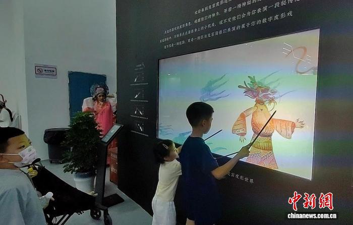 8月15日,2025“新疆是个好地方”非遗援疆主题展示活动在新疆和田约特干故城开幕。图为孩子们在现场体验“龙宫戏影——数字皮影戏触控互动体验”装置。 中新社记者 应妮 摄