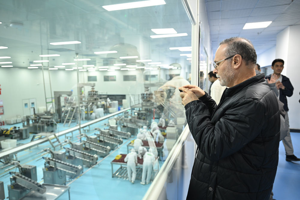 4月26日,外宾在参观位于喀什的一家农业科技有限公司时拍照记录工厂生产线。新华社记者 辛悦卫 摄