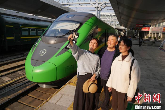 3月28日，中老铁路第5000万名旅客孙怡薇一家在列车前合影。中新社记者 刘冉阳 摄