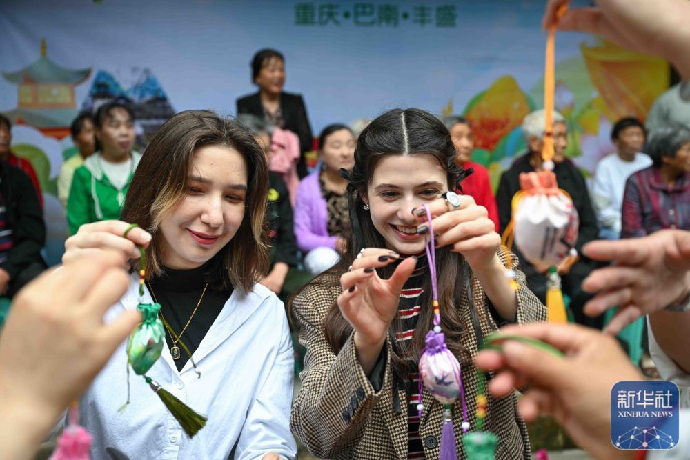 5月28日，在重庆市巴南区丰盛古镇，古镇居民与留学生一起制作香囊。