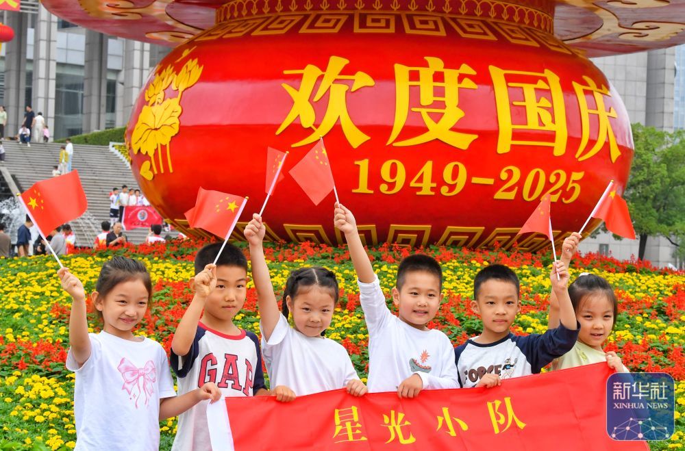 ↑ 10月1日,小朋友在安徽省合肥市蜀山区市民广场国庆主题花篮前拍照。新华社发(陈三虎摄)