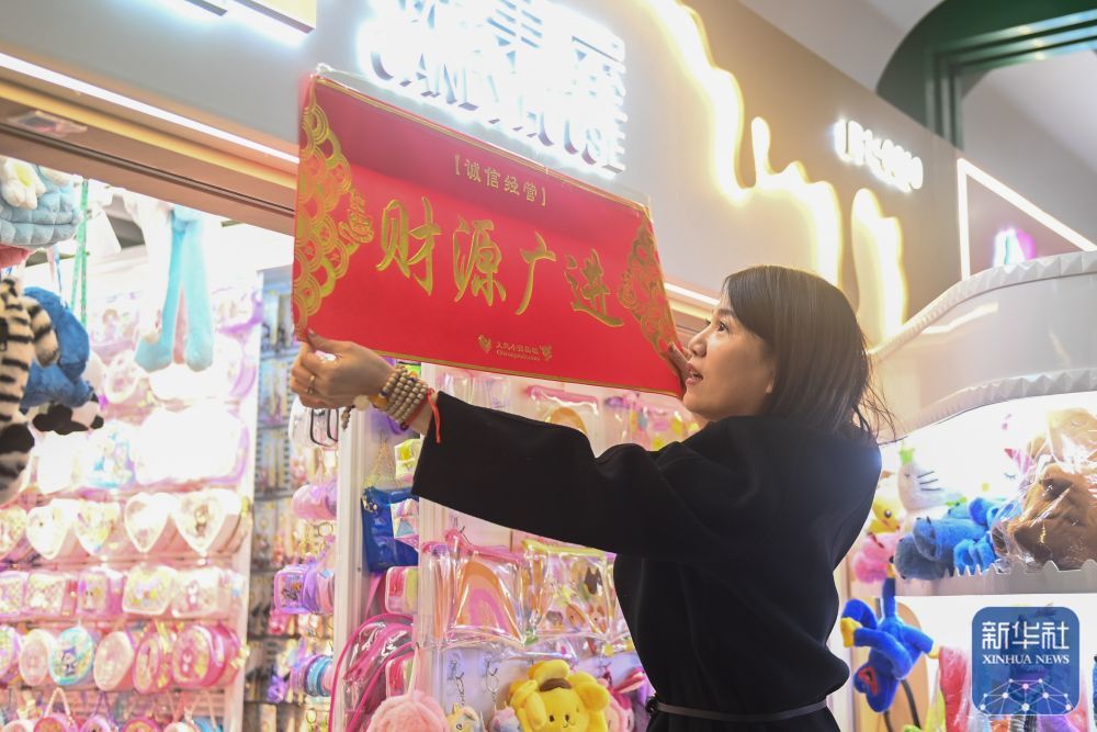 ↑2月9日,义乌国际商贸城的商户在店铺门口张贴领取的新春横幅。
