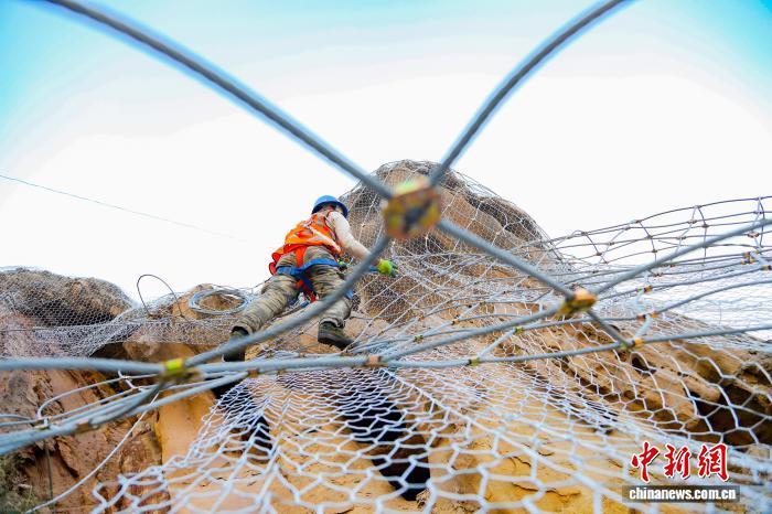 图为兰州铁路局兰州西工务段铁路职工固定柔性主动钢丝网。北方汛期结束后,兰州西工务段加大兰新、兰青、包兰铁路沿线陡峭山体、危岩落石地段的排查整治,按照轻重缓急,在陡峭山体、隧道口等重点地段,通过加装柔性主被动防护钢丝网和搜山扫石的方式,有效防止风化落石、活石、浮石等掉落到铁路线路上。王光辉 摄
